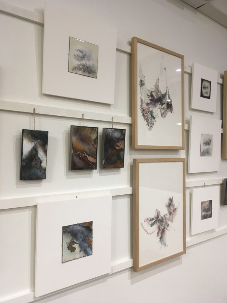 Scénographie de l'exposition Au bord du rivage de Natacha Baluteau : série de dessins à l'encre et émaux contemporains aux textures minérales. Accrochage à l'italienne.