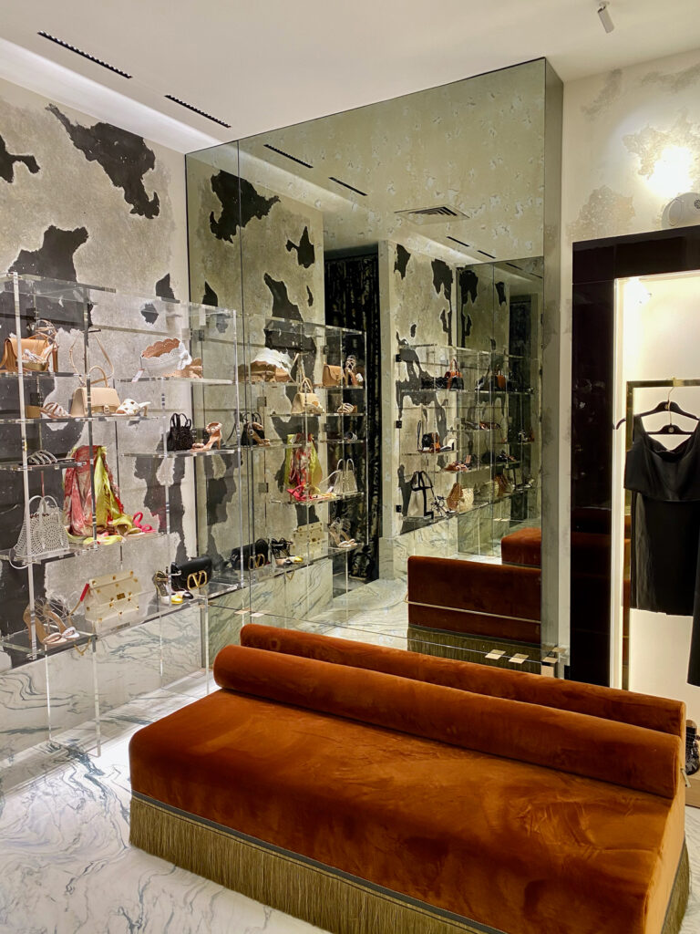 Vue d'une boutique de luxe avec murs texturés et mobilier en velours, illustrant l'intégration d'émaux d'art dans un projet d'architecture d'intérieur sur mesure.