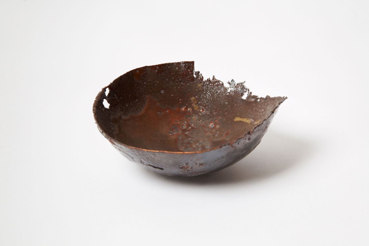 Œuvre d'art contemporain en émail sur cuivre de la série Archéo par Natacha Baluteau. Sculpture en forme de bol aux textures magmatiques rousses et brunes, avec une bordure déchirée et ajourée. L'objet semble issu de fouilles archéologiques.