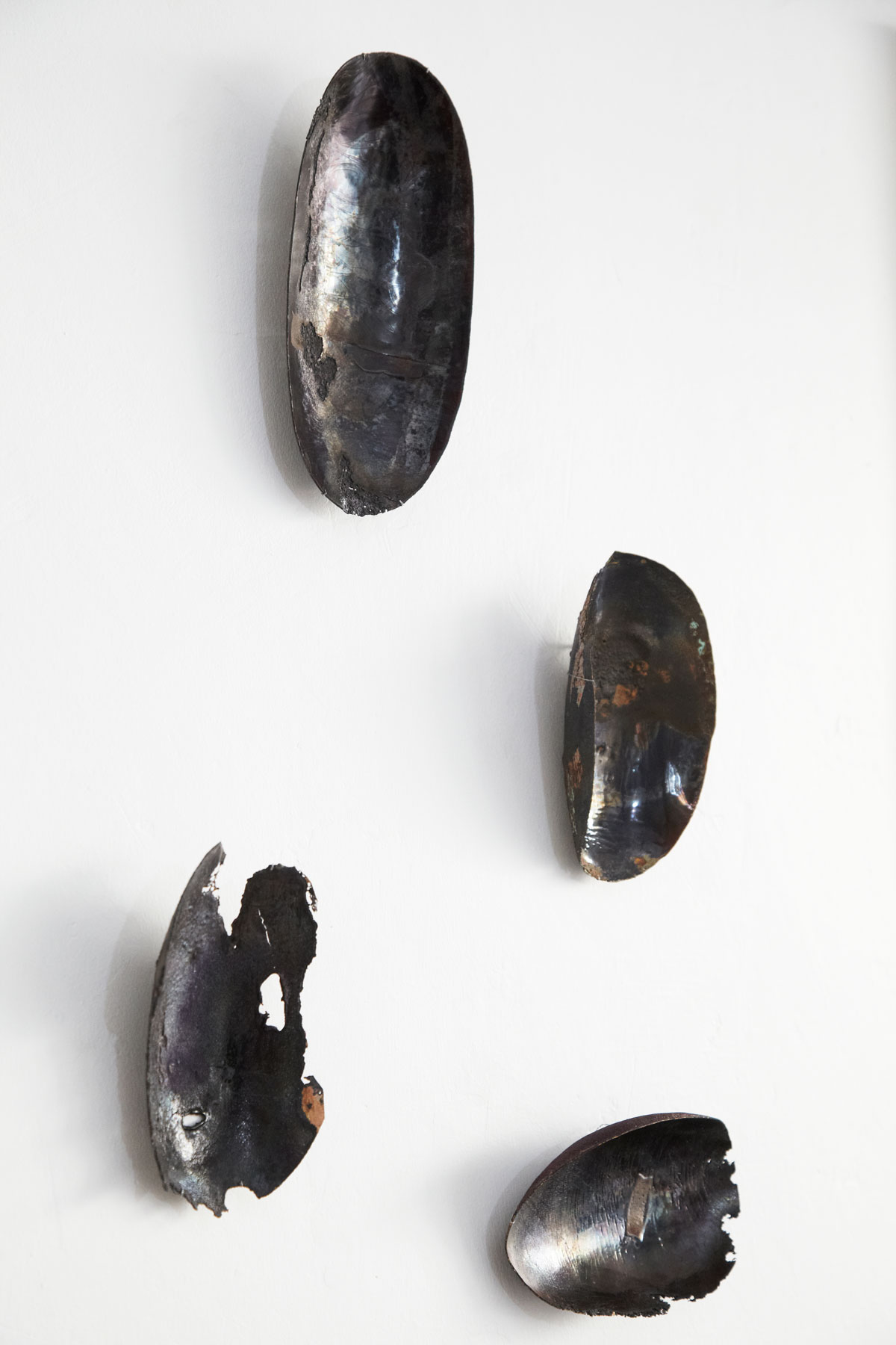 Installation murale de la série Archéo par l'artiste plasticienne Natacha Baluteau. Œuvre d'art contemporain en émail sur cuivre composée de quatre pièces concaves uniques aux textures d'oxydation sauvages.