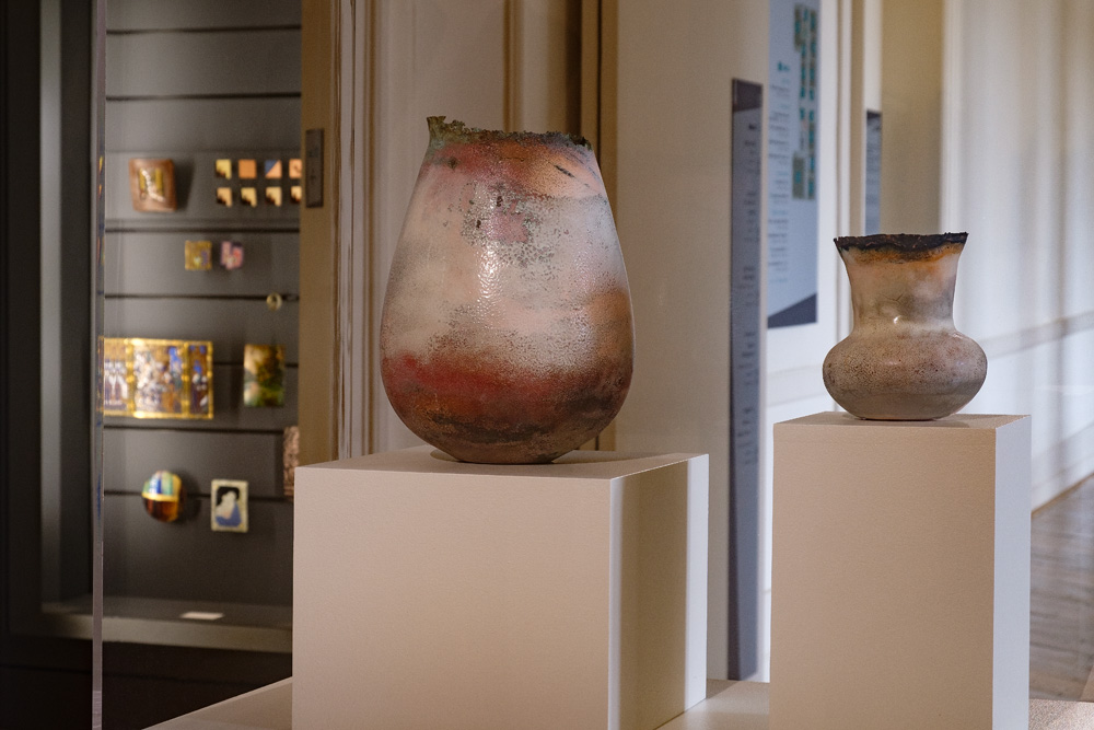 Deux vases en émaux contemporains, dont le col du plus grand est dentelé. La couleur dominante est blanc, ivoire et rose pâle, cuivré. Réalisé par la plasticienne Natacha Baluteau, fond permanent du Musée-des Beaux-Arts de Limoges.